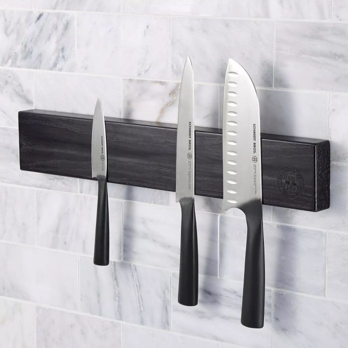 The wall-mounted bar with three knives attached to it