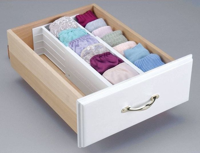 A drawer organized into three separate compartments, each holding socks and underwear in an orderly fashion.