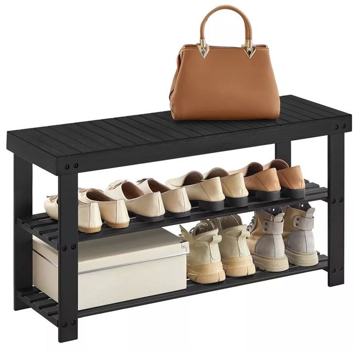 A black shoe rack with a brown handbag resting on top, several pairs of shoes neatly arranged, and a storage box placed on the two lower shelves — the ideal solution for organizing your entryway.