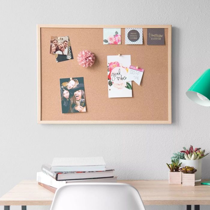 A bulletin board with various items pinned on it in an office setting, offering a practical and organized way to display important papers and photos.