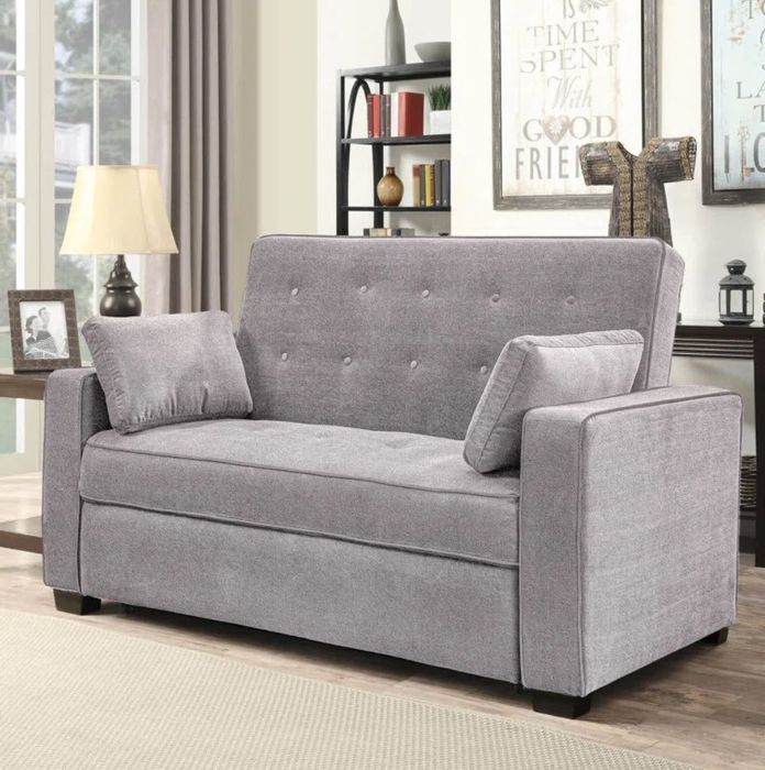 a compact tufted loveseat accompanied by two petite pillows