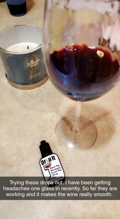 Reviewer's photo of a glass of red wine and a Drop It bottle on the counter. The caption reads,