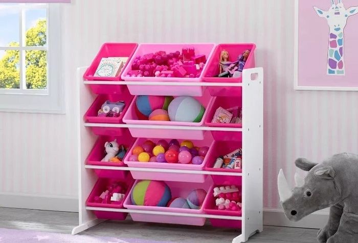 Toy organizer featuring pink and white bins, filled with a variety of colorful toys, in a children's room surrounded by plush animal decor
