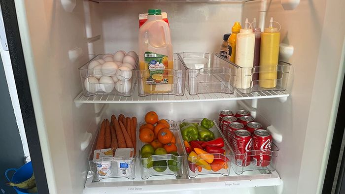 A review photo showing a fridge neatly organized with eight clear bins, each holding different items.