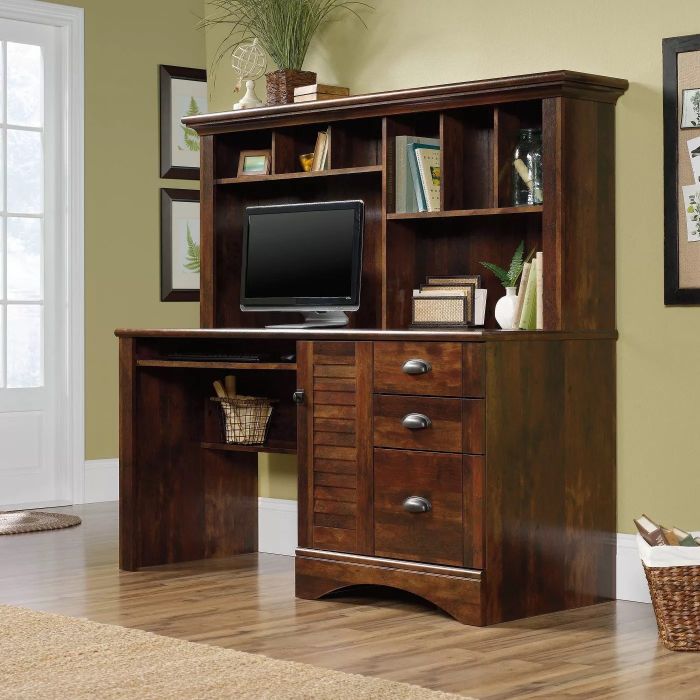 A wooden desk with built-in shelves and drawers, providing ample space for a monitor and decorative items. This desk is ideal for keeping your home office organized.