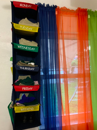 Closet organizer filled with outfits for each day of the week, neatly hanging on a teenager's curtain rod