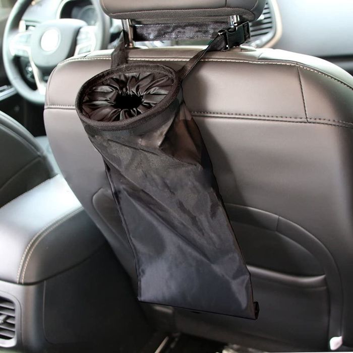 A collapsible fabric trash bin with handles wrapped around the passenger seat and a sealed top