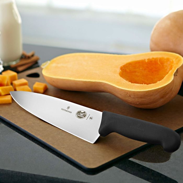 The knife positioned next to a squash.