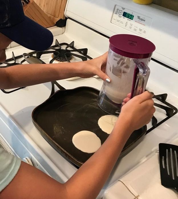 reviewer photo showing someone using the batter dispenser to make pancakes