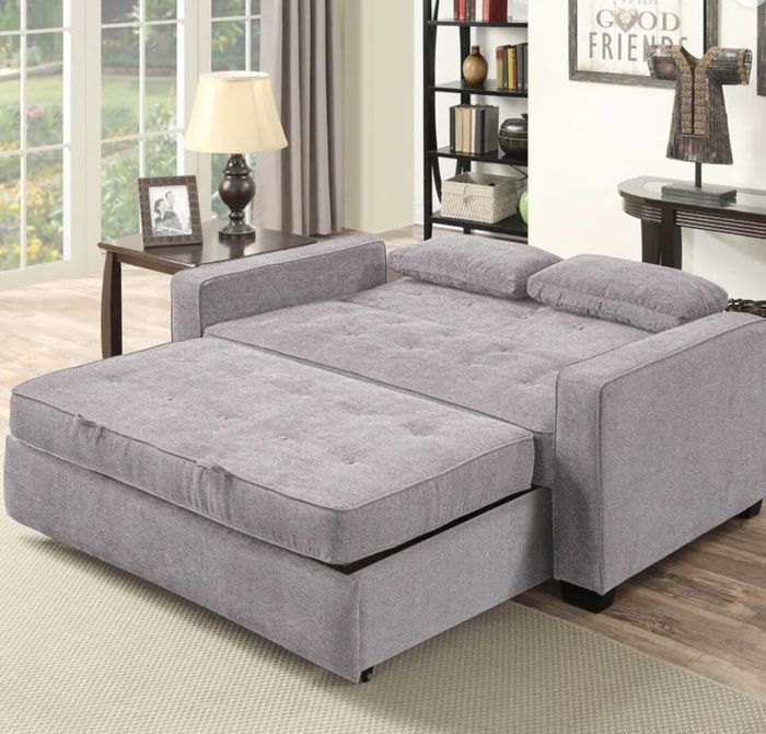 a gray tufted pullout sofa bed with two small decorative pillows