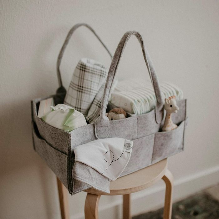 A minimalist felted carrier with diaper-changing essentials in the main pockets and toys in the side pockets