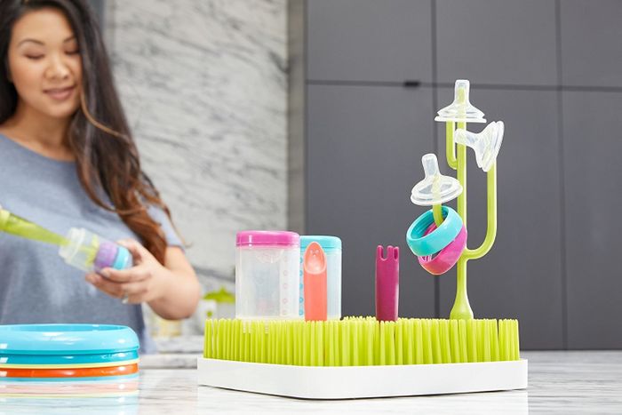 A person drying bottles and tops on a drying rack designed with cactus and grass motifs