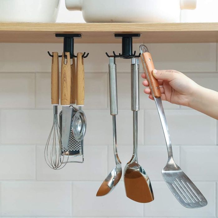 Picking out a kitchen utensil from a mounted holder situated under a shelf.