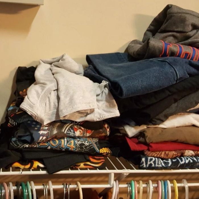 A chaotic pile of T-shirts stacked above a closet rod