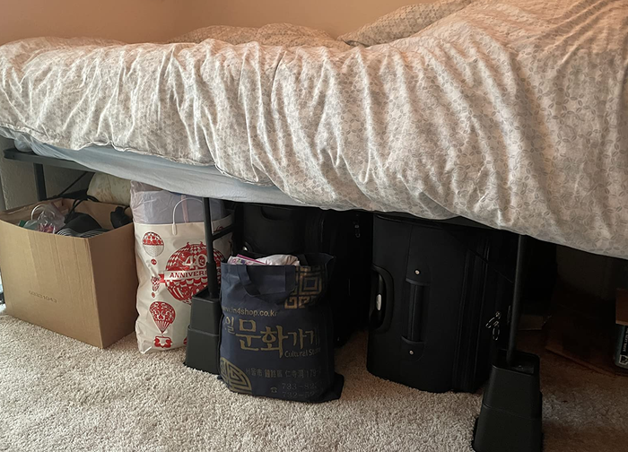 a reviewer's image of a bed elevated on risers with storage bags and boxes neatly placed underneath
