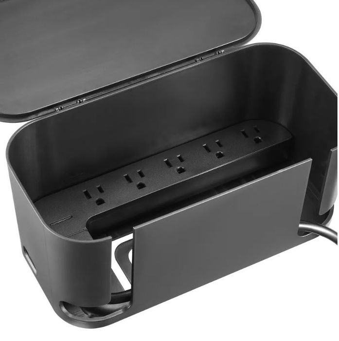 A cable management box with its lid open, revealing a power strip inside and cords neatly routed through side openings.