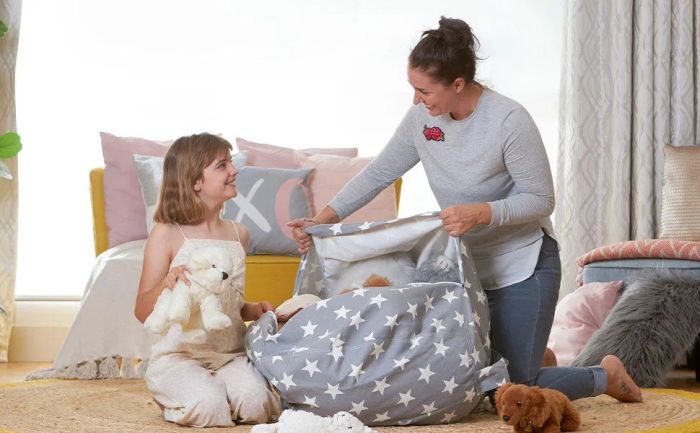 A young child and their parent packing the bean bag with toys.