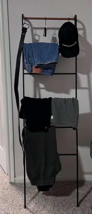 a reviewer's photo of the ladder rack displaying various clothing items neatly hung on it