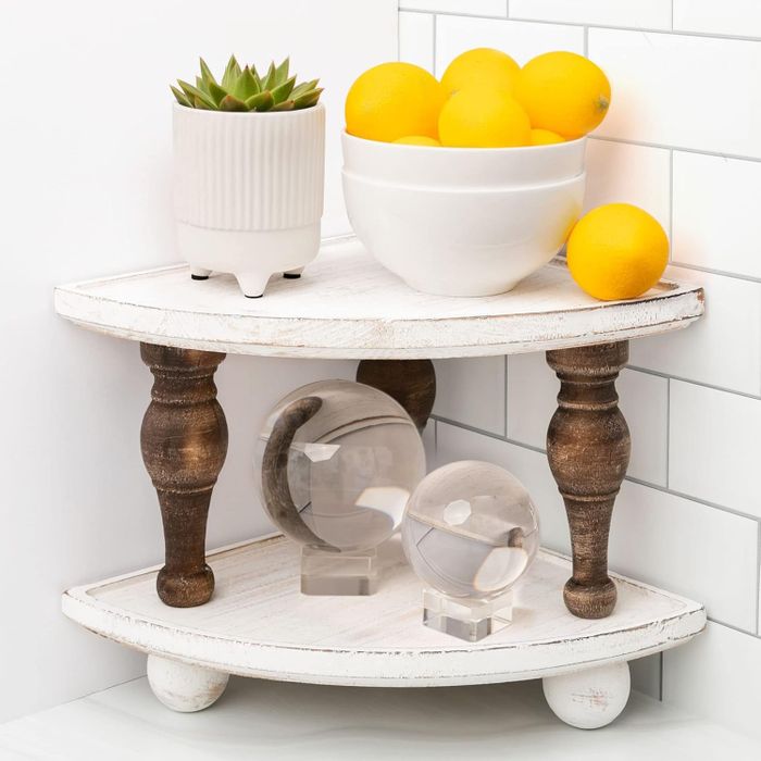 A corner shelf displaying a plant, a bowl of lemons, and two transparent decorative spheres, adding a stylish touch to your home decor.