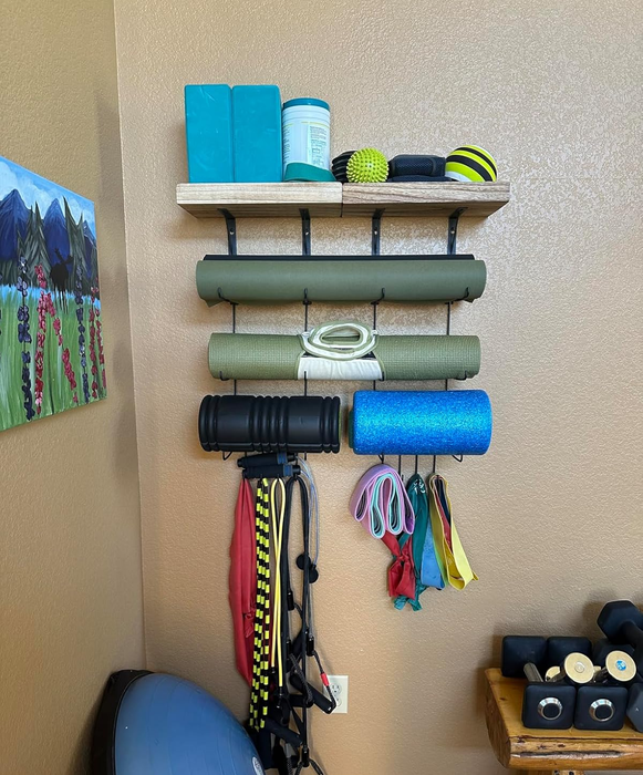 Home gym equipment neatly arranged on wall shelves, featuring mats, resistance bands, foam rollers, weights, and a medicine ball