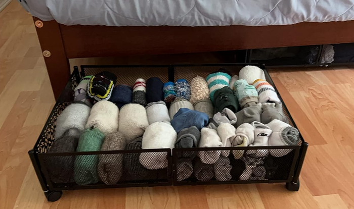 a reviewer's photo of the same bed with the rolling bin extended, filled with socks