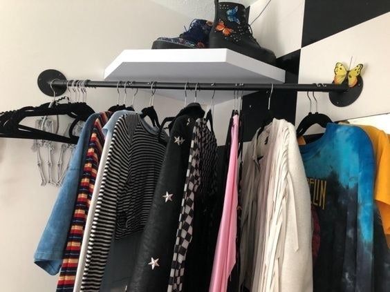 a reviewer's photo of the corner clothing rod with garments neatly hung