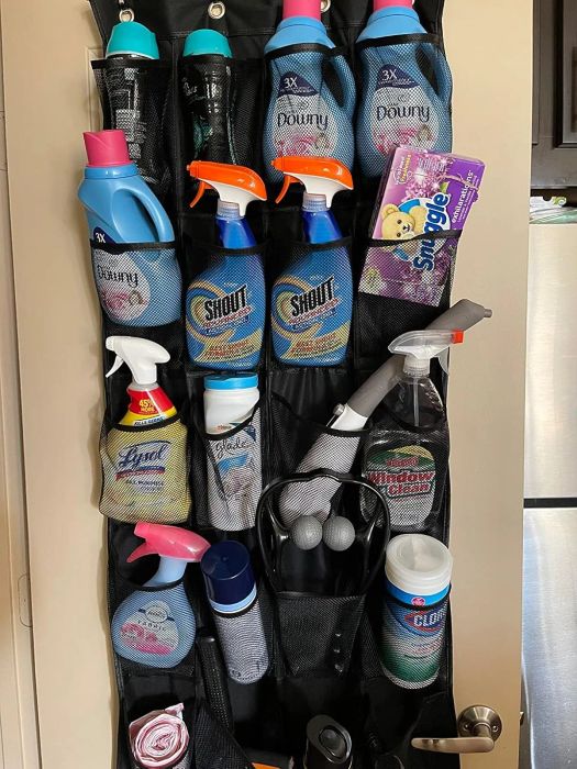 An over-the-door organizer filled with various laundry and cleaning supplies such as detergents, sprays, wipes, a lint roller, and gloves