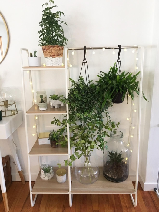 a reviewer's photo of the clothing rack with attached shelves, adorned with various plants