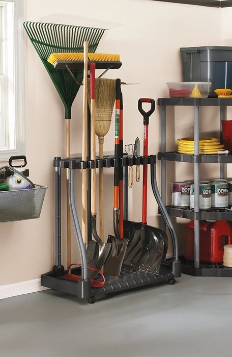 A rack in the garage holding rakes and heavy shovels neatly in place.