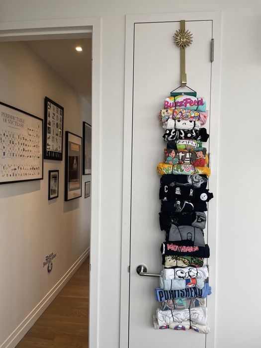A closet door with several shirts rolled up and hanging from stretchy loops attached to a hook at the top of the door