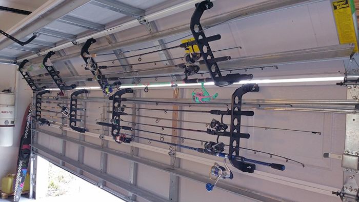 An inside view of a garage with fishing rods stored horizontally on racks attached to the garage doors