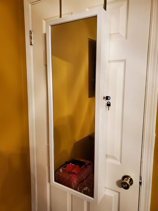 A reviewer's photo of the cabinet closed, functioning as an over-the-door mirror