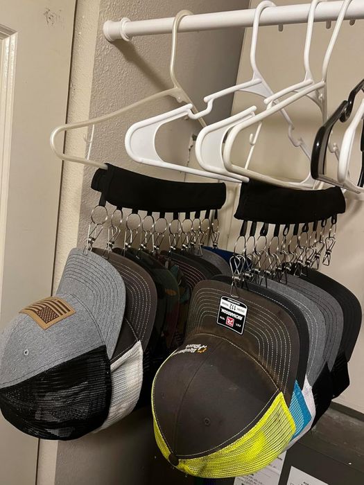 Hats neatly organized on a hanger with clips inside a closet, demonstrating an efficient space-saving solution for cap storage