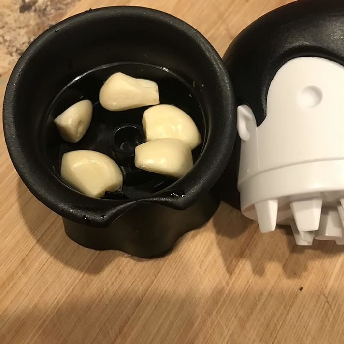 A mug shaped like a Stormtrooper helmet, filled with garlic cloves and accompanied by its matching lid