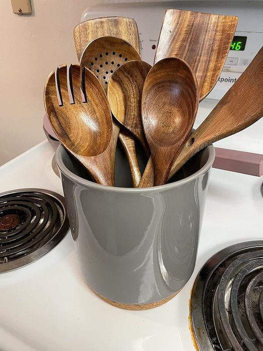 A collection of wooden cooking tools neatly arranged in a gray holder on a stovetop. Ideal for home cooks who prefer natural and eco-friendly kitchen utensils