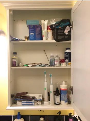 A photo from the reviewer showing their bathroom cabinet before installing the organizer.