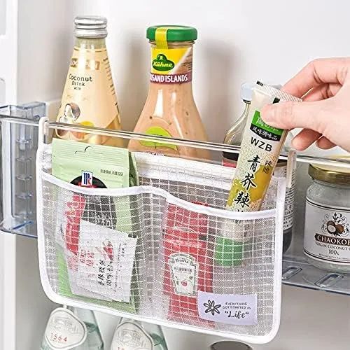 A hand placing a packet into a mesh refrigerator storage organizer, already filled with various condiments