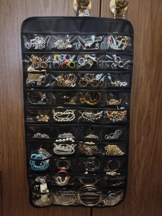 Hanging jewelry organizer filled with an assortment of earrings, necklaces, and bracelets, neatly arranged in clear pockets
