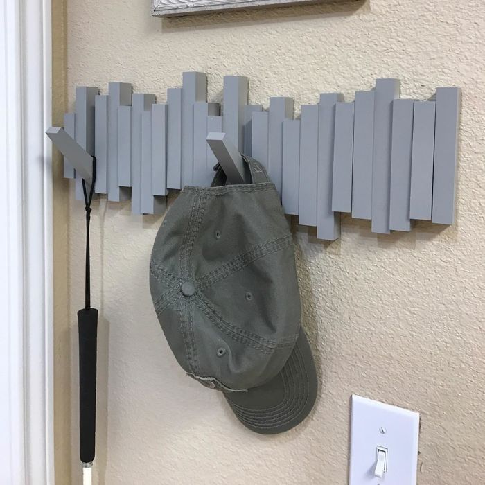 a reviewer's photo of the gray wall-mounted hooks holding a hat and an umbrella
