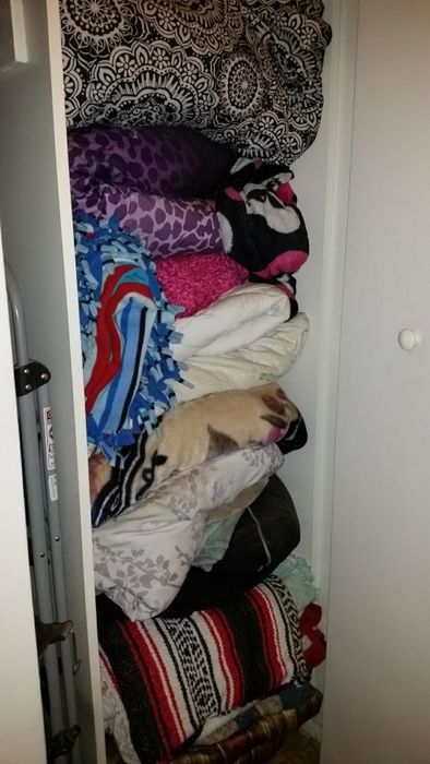 Reviewer's before photo of a cluttered closet overflowing with blankets and towels