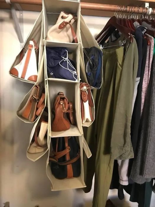 Reviewer photo of the fabric hanger in a closet, with four central compartments and three additional ones on each side, all filled with purses and bags.