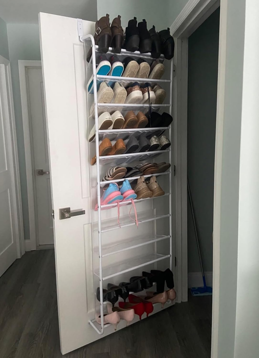 a reviewer's photo of the shoe organizer mounted on a door, filled with various types of footwear