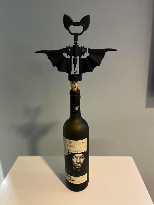 A bat-shaped wine opener placed on top of a wine bottle