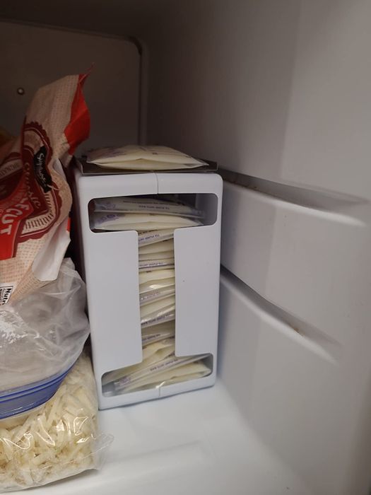 A freezer organizer with stacked breast milk storage bags placed alongside other frozen food items.