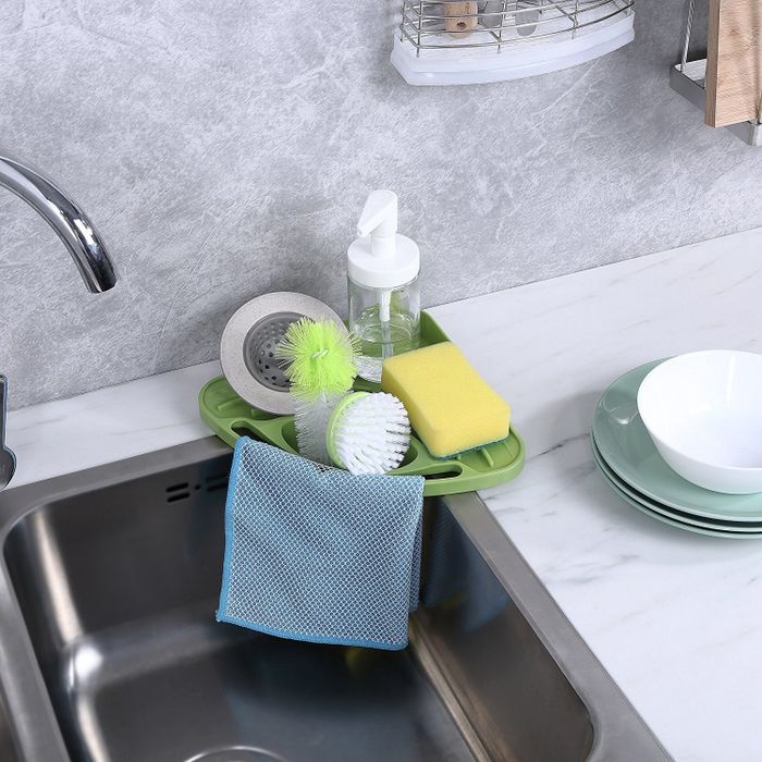 A kitchen sink featuring a triangular sponge and soap holder placed in the corner