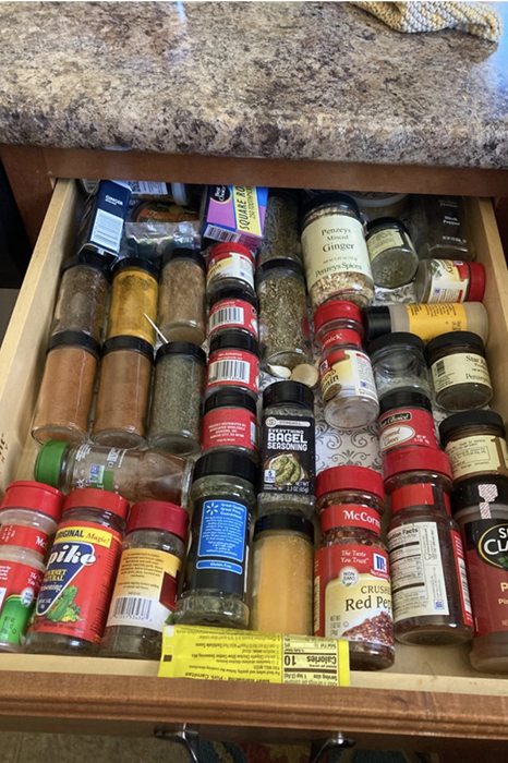 A reviewer's before photo of a cluttered drawer overflowing with disorganized spice jars