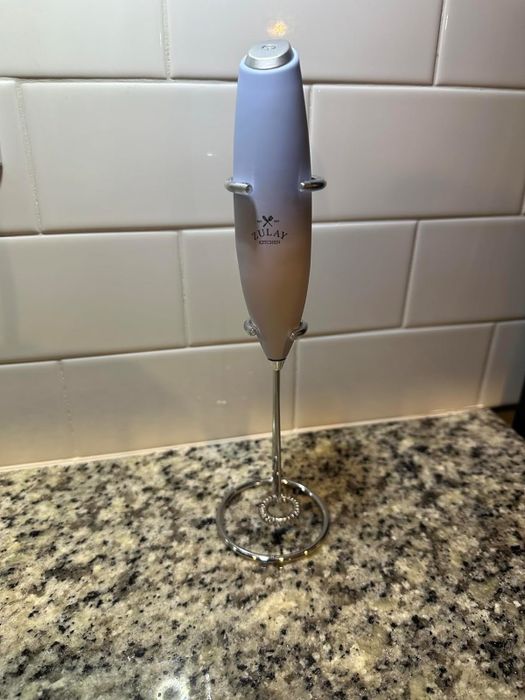 A handheld milk frother displayed on a kitchen countertop