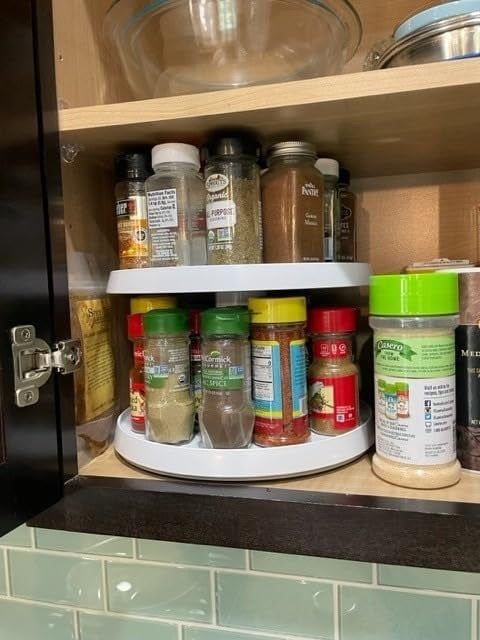 A kitchen cabinet with spices and small bottles neatly organized on a two-tier turntable.