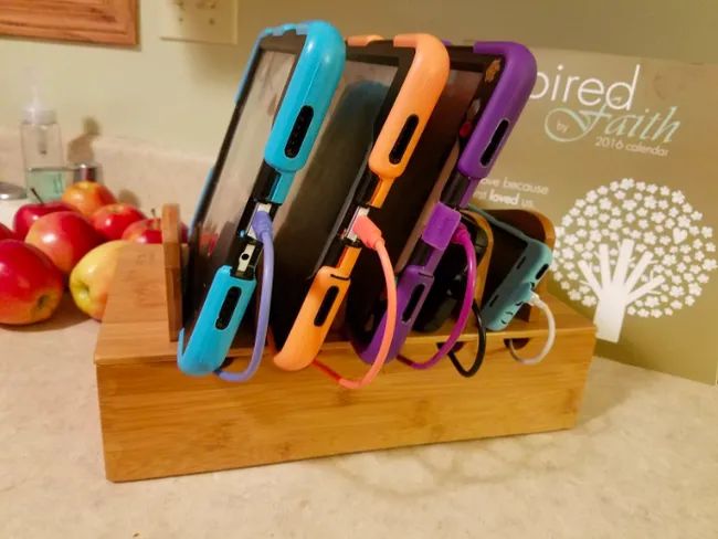 A wooden rack with designated slots to hold phones and tablets as they charge