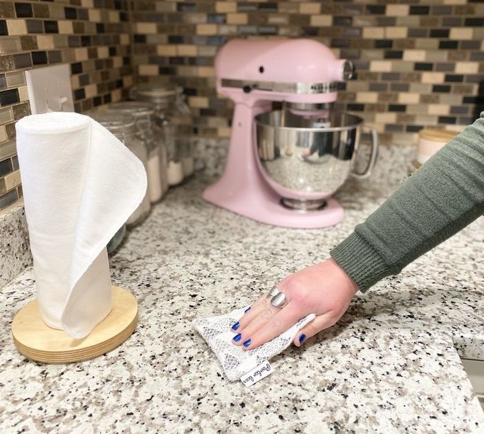 A model demonstrating the use of a reusable sponge to clean a kitchen countertop